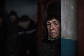 Ukrajinská žena v Doněcku čeká, až přejde střelba na snímku z února (ilustrační snímek).