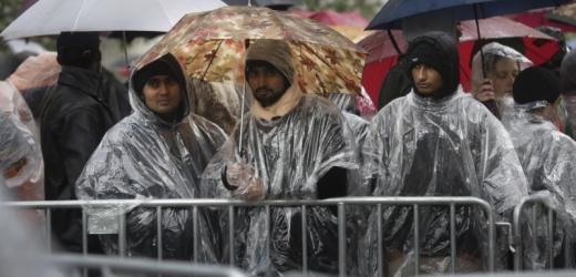 Běženci čekají v dešti před registračním centrem v Berlíně.